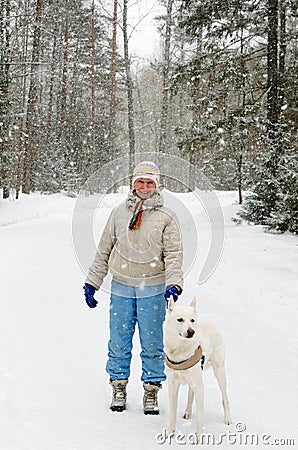 Woman with a dog on a walk in woods during a snowfall