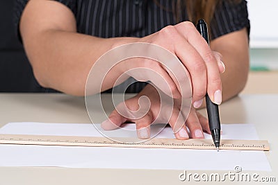 Woman is drawing a line with pen and ruler
