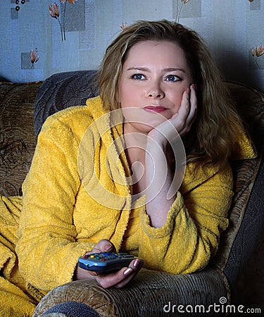 Woman in dressing gown watches TV