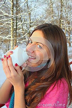 Woman drinks warm tea in winter park