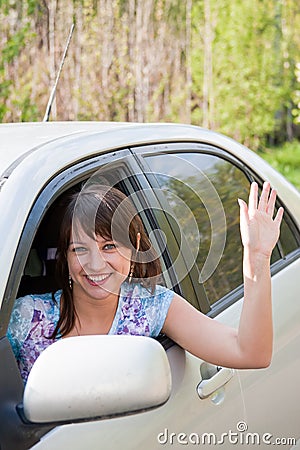 Woman a driver after the helm of car waves a hand