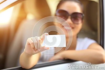 Woman driver sit in car hold blank business card