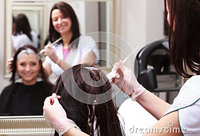 Woman dying hair in hairdressing beauty salon. By hairstylist.