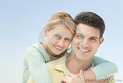 Woman Embracing Man From Behind Against Clear Blue Sky