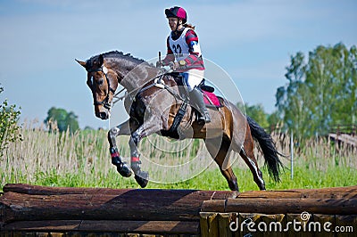 Woman eventer on horse is Drop fence in Water jump