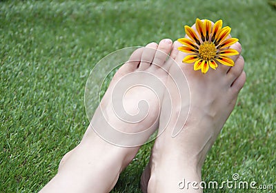 Woman feet on the grass with flower