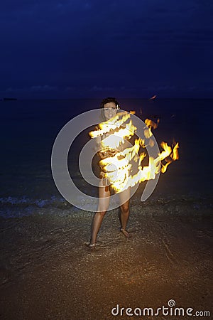 Woman with fire on the beach at night