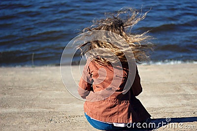 Woman with flying blonde curly hair on sea background