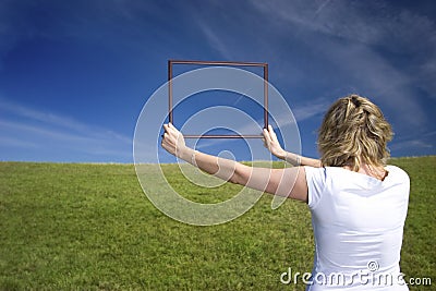 Woman with frame on big meadow