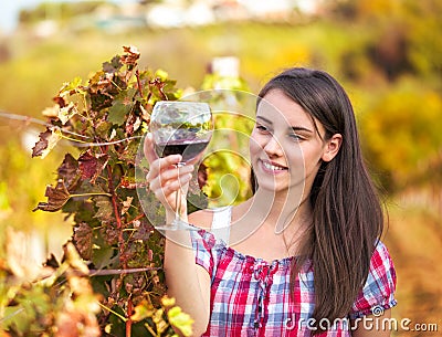 Woman with glass of wine in the vineyard.