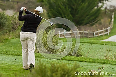 Woman golfer swinging driver on tee box