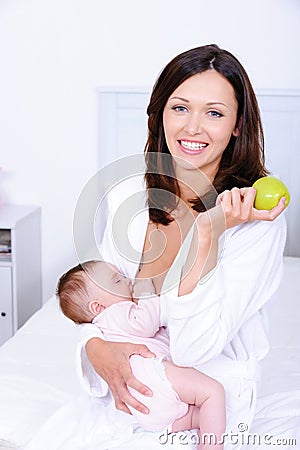 Woman with green apple breastfeeding her baby