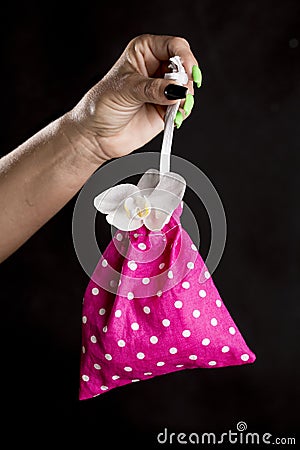 Woman hand holding a little purple storage bag with orchid