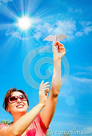 Woman hand starts paper plane in blue sky