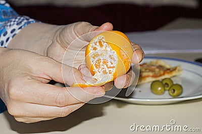 Woman hands opening tangerine