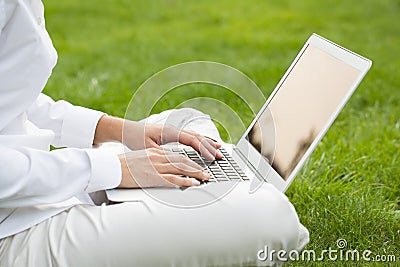 Woman hands typing on a laptop keyboard, in garden