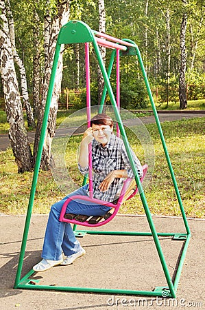 Woman has a rest on a swing in the garden