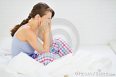 Woman with head ache sitting on bed