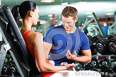 Woman and Personal Trainer in gym with dumbbells