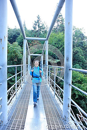 Woman hiker walking at bridge in mountain peak