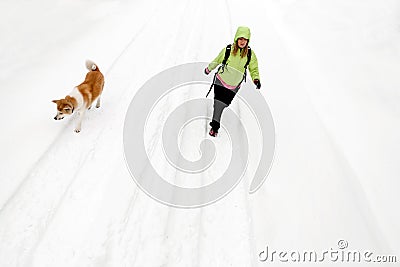 Woman hiking with dog on winter road and snow