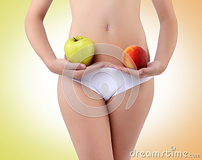 Woman holding an apple and peach with his hands near the belly
