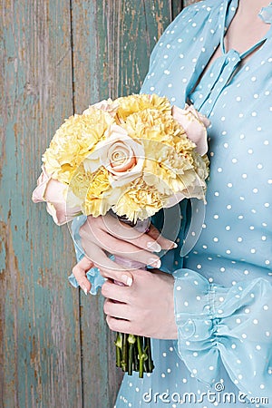 Woman holding bouquet of yellow carnation and pink roses