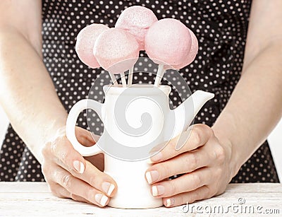 Woman holding jug of pink cake pops