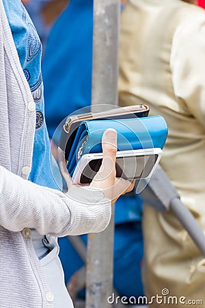 Woman holding one purse and two mobile phone in her hand