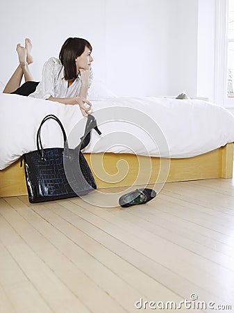 Woman Holding Shoe While Lying In Bed