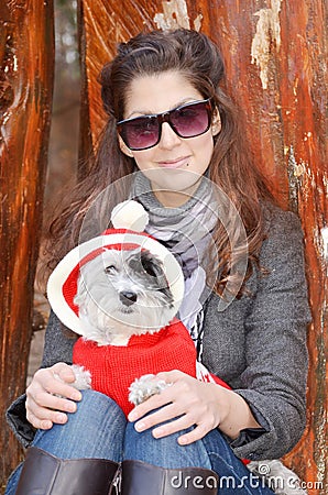 Woman hugging her dog dressed with red christmas hats