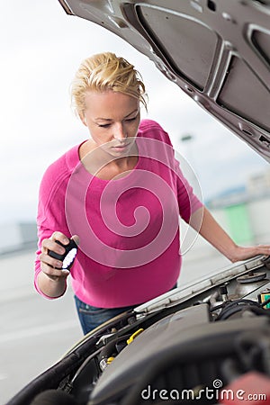 Woman inspecting broken car engine.
