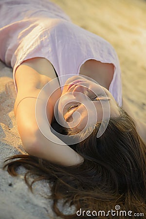 Woman laying down on a sand beach on sunset