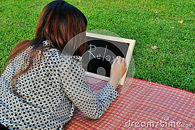 Woman lie down on grass and write on blackboard