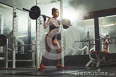 Woman lifting barbell with weight in gym