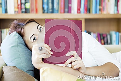 Woman looking from behind book