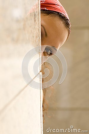 Woman looking behind a wall