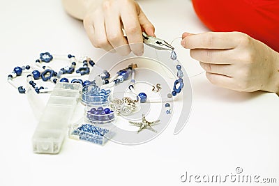 Woman making necklase from colorful plastic beads on light background