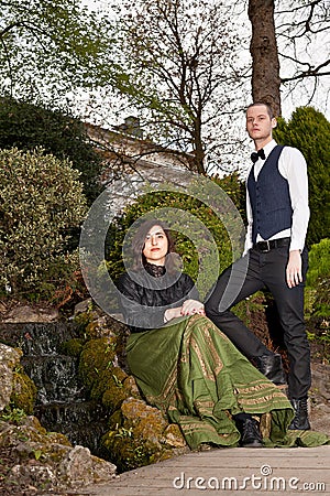 Woman and man in Victorian fashion near waterfall in park