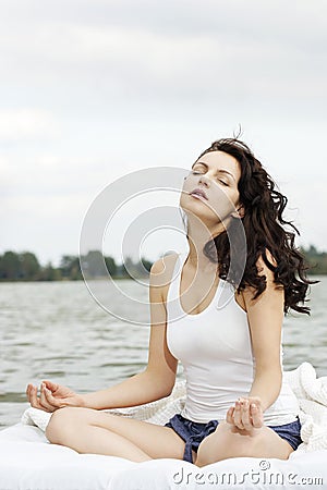 Woman meditates on the white bed in the sea
