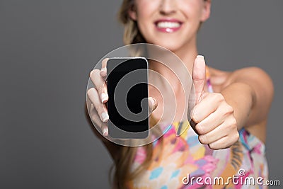 Woman with mobile giving a thumbs up of approval