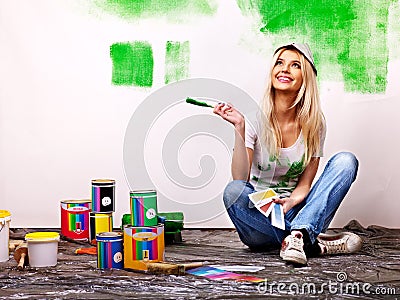 Woman paint wall at home.