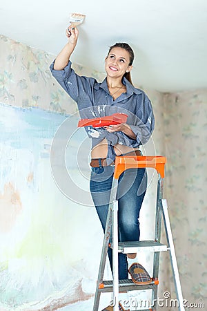 Woman paints ceiling with brush