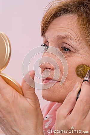 Woman paints his face and looks in the mirror