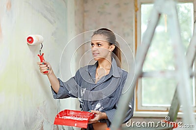 Woman paints wall with roller