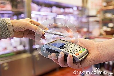 Woman paying with NFC technology on mobile phone, in supermarket