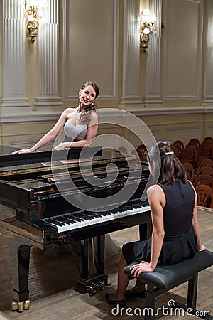 Woman pianist sits at the piano and beautiful singer