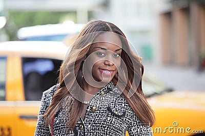 Woman posing with a taxi in the background