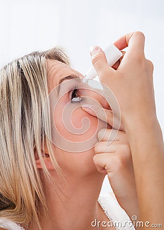 Woman pouring drops in her eyes