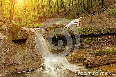 Woman practices yoga in nature, the waterfall. Urdhva phanurasana pose